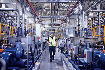 Leadec employee with tablet walking on shopfloor of Food & Beverage factory.